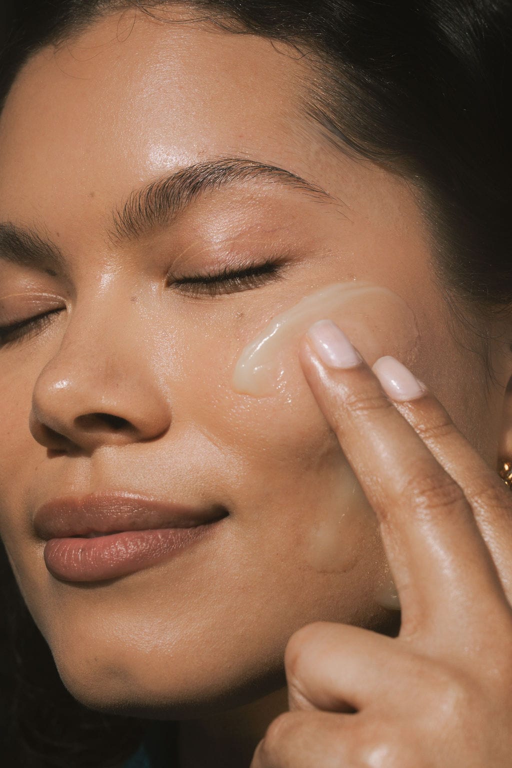 Gentle fingertip application of balm to a cheek